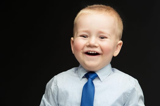Handsome laughing funny little boy wearing shirt and blue tie. True emotions. Studio shot. Horizontal. Copy space.