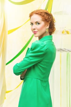 Beautiful young woman with braided red hair standing in green long jacket