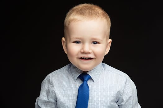 Handsome smiling funny little boy wearing shirt and blue tie. True emotions. Studio shot. Horizontal. Copy space.