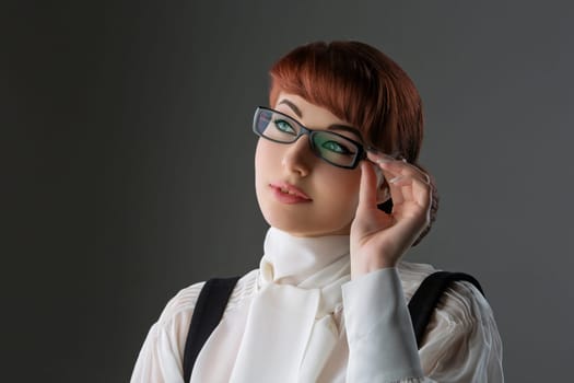 Closeup of beautiful young woman in white blouse and glasses over grey background