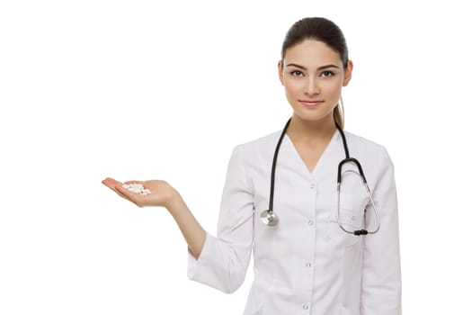 Beautiful young woman dressed as doctor holding handful of white pills. Isolated over white background