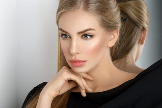 Beautiful young woman with blond hair and makeup covered with piece of black fabric. Copy space.