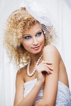 Beautiful young bride with bright make-up and fancy hairstyle wearing hat. Over white background.
