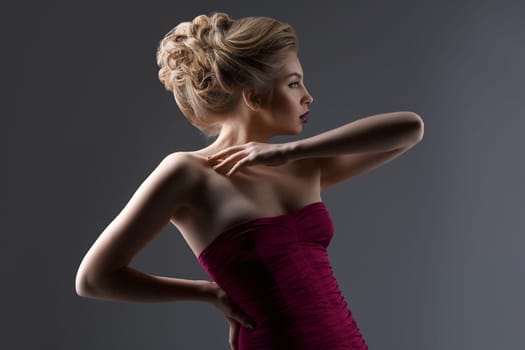 Beautiful young woman with dark lips and stylish hairdo. Beauty shot over dark grey background. Copy space.
