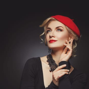 Beautiful lady in red beret. Beauty portrait. Red lips. Over black background. Copy space.