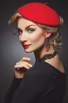 Beautiful lady in red beret. Beauty portrait. Red lips. Over black background.