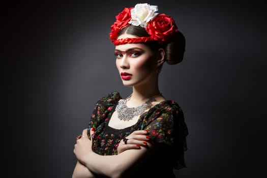 Beautiful young woman with bright red make up looking like Frida Kahlo. Over black background. Copy space.