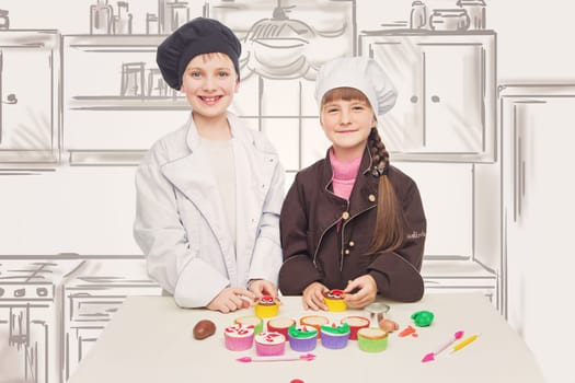 Beautiful boy and girl in chef clothes making christmas cupcakes. Children standing over kitchen drawing background.