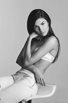 Beautiful young slim woman in white bra and leather pants with zippers. Fashion shot. Over white background. Copy space.