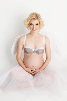 Beautiful young pregnant woman with angel wings