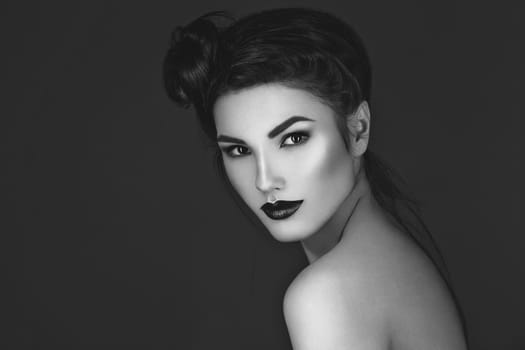 Beautiful young woman with dark red lips and hairdo. Beauty shot. Over grey background. Copy space.
