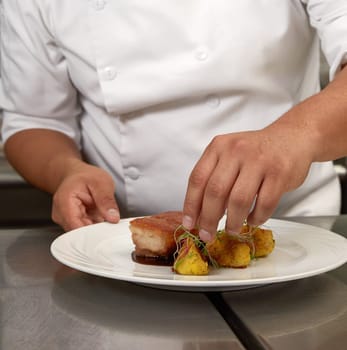 Chef Decorating Traditional Peruvian Meal Called Chicharron de Panceta de Cerdo.