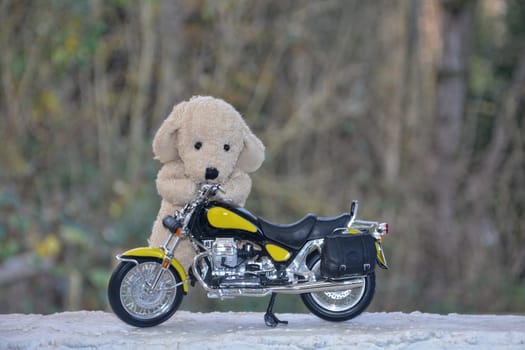 White stuffed animal dog stands behind a motorcycle in nature