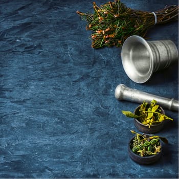 Bundle herbs and mortar with pestle on slate background.Copy space