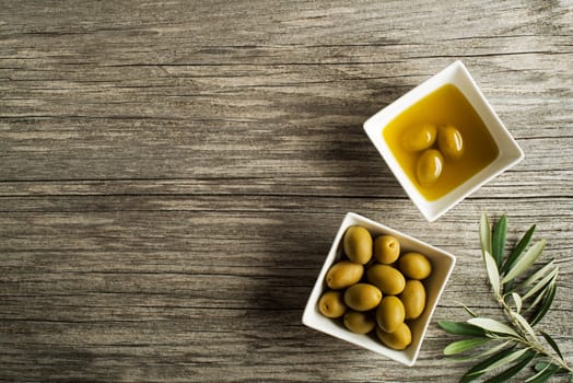 Olive oil with fresh olive fruit on wooden background.