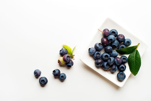 Fresh blueberries with green leaves on white background