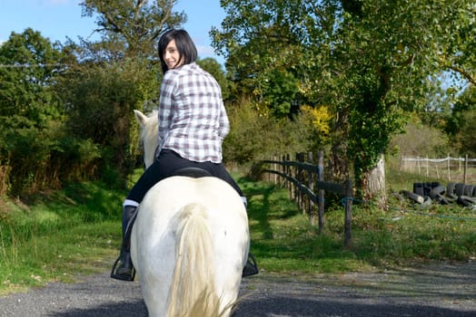 young beautiful brunette woman riding white horse