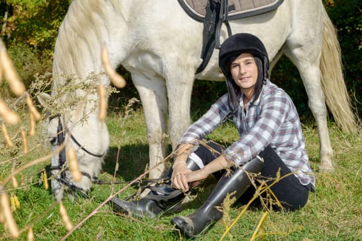 pretty brunette young woman with a white horse riding