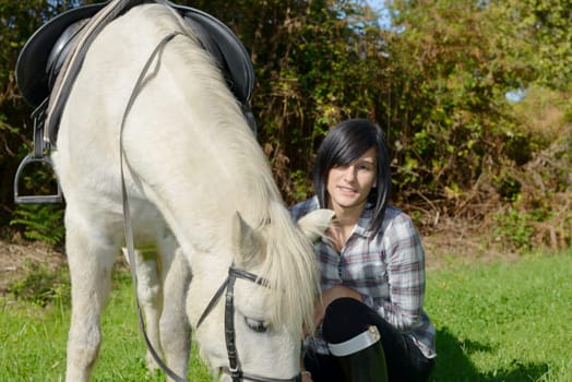 pretty brunette young woman with a white horse riding