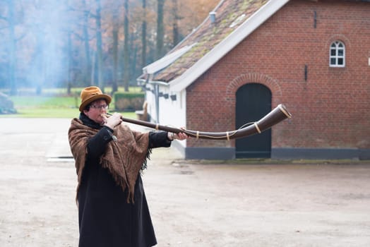 OLDENZAAL, NETHERLANDS - NOVEMBER 27, 2016: Unknown woman blowing a so called "midwinterhorn"", a traditional handmade wooden instument. It is used in the advent period in some eastern parts of the netherlands"