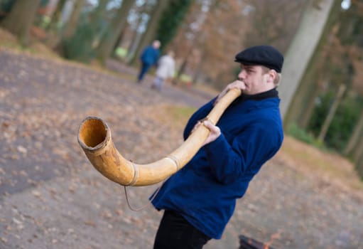 OLDENZAAL, NETHERLANDS - NOVEMBER 27, 2016: Unknown man blowing a so called "midwinterhorn"", a traditional handmade wooden instument. It is used in the advent period in some eastern parts of the netherlands"