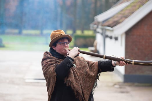 OLDENZAAL, NETHERLANDS - NOVEMBER 27, 2016: Unknown woman blowing a so called "midwinterhorn"", a traditional handmade wooden instument. It is used in the advent period in some eastern parts of the netherlands"
