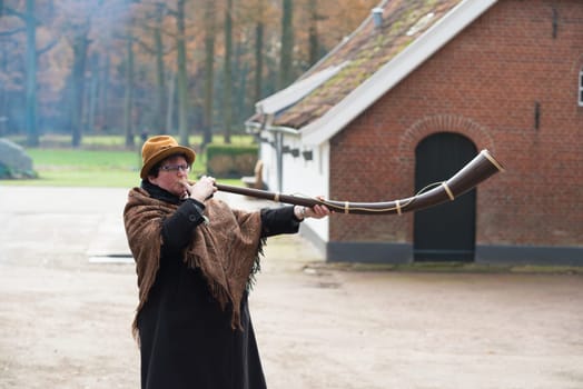 OLDENZAAL, NETHERLANDS - NOVEMBER 27, 2016: Unknown woman blowing a so called "midwinterhorn"", a traditional handmade wooden instument. It is used in the advent period in some eastern parts of the netherlands"