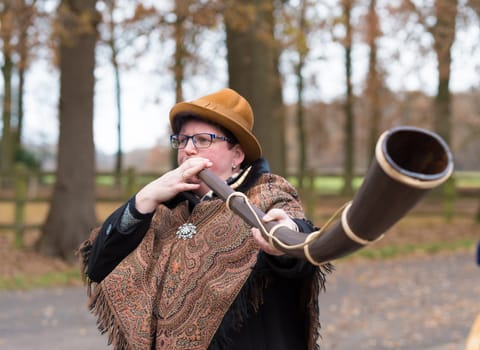 OLDENZAAL, NETHERLANDS - NOVEMBER 27, 2016: Unknown woman blowing a so called "midwinterhorn"", a traditional handmade wooden instument. It is used in the advent period in some eastern parts of the netherlands"
