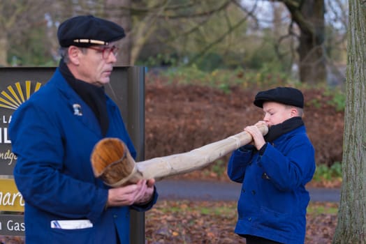 OLDENZAAL, NETHERLANDS - NOVEMBER 27, 2016: Unknown young boy blowing a so called "midwinterhorn"", a traditional handmade wooden instument. It is used in the advent period in some eastern parts of the netherlands"