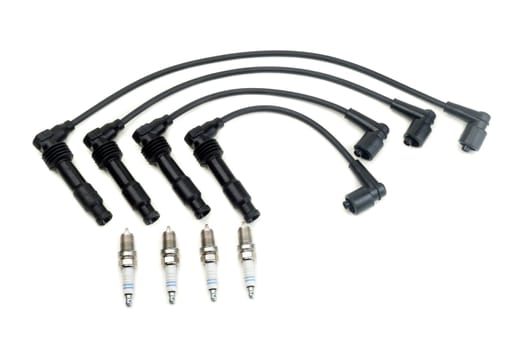 Four spark plugs and a set of high-voltage wires. Isolate on white.