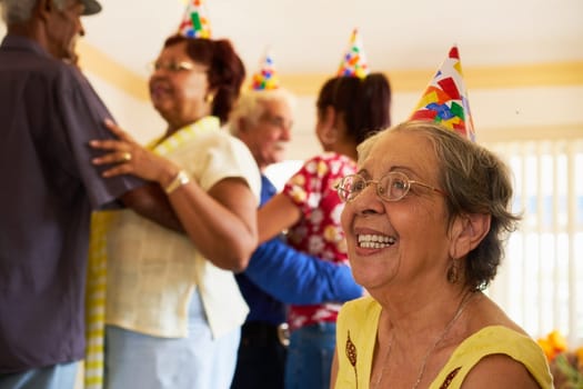Group of old friends and family celebrating senior birthday party in retirement home. Patient woman smiling in hospice.