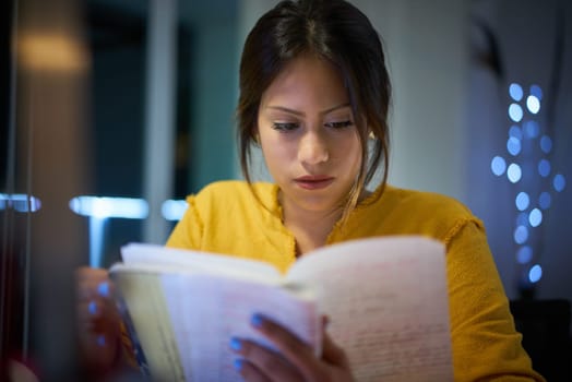 Young woman doing homework at night. Tired hispanic girl and college education. Female student studying for next day exam