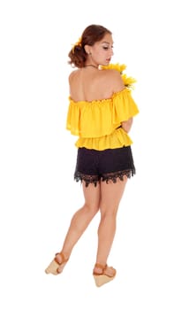 Gorgeous young woman in yellow blouse holding sunflowers, looking.over her shoulder, standing isolated for white background..