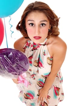 A beautiful woman kneeling on floor and looking up with a lollypop and.two balloons, isolated for white background..
