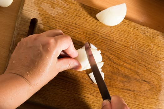 Cutting and chopping an onion on a wooden board with a knife