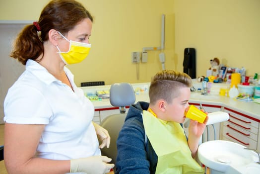 teenager is treated by female dentist in dental surgery