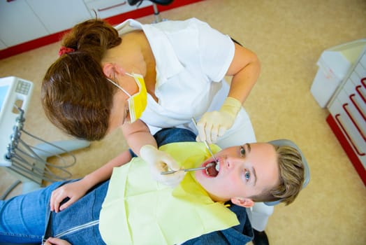 teenager is treated by female dentist in dental surgery