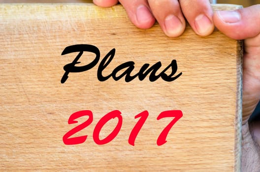 Human hand over wooden background and plans 2017 text concept