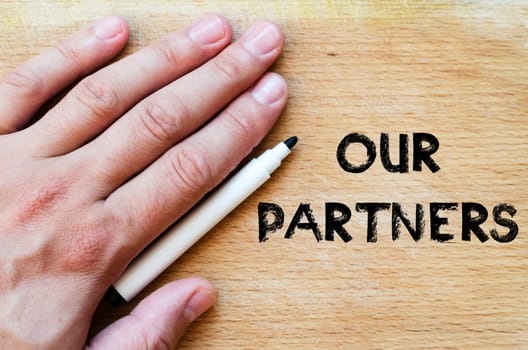 Human hand over wooden background and our partners text concept
