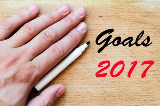 Human hand over wooden background and goals 2017 text concept