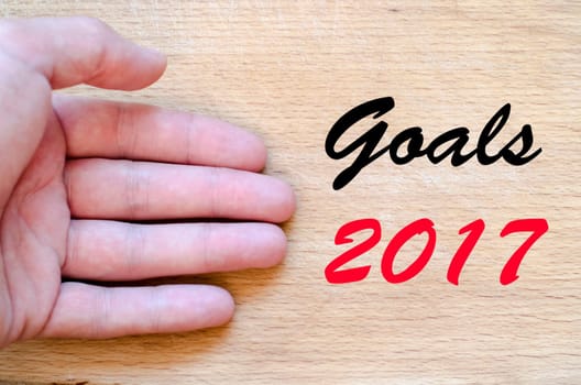 Human hand over wooden background and goals 2017 text concept