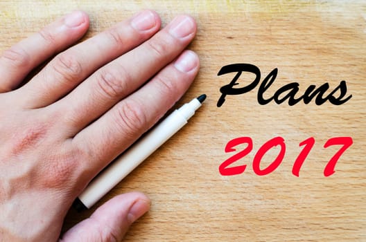Human hand over wooden background and plans 2017 text concept