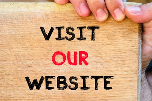 Human hand over wooden background and visit our website text concept