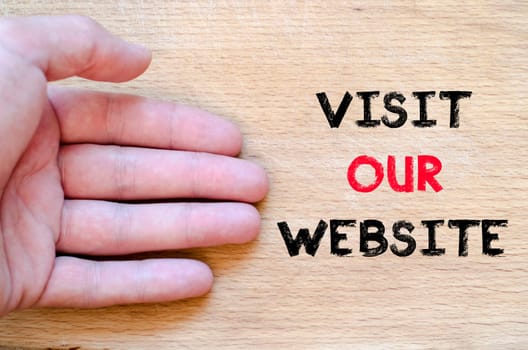 Human hand over wooden background and visit our website text concept