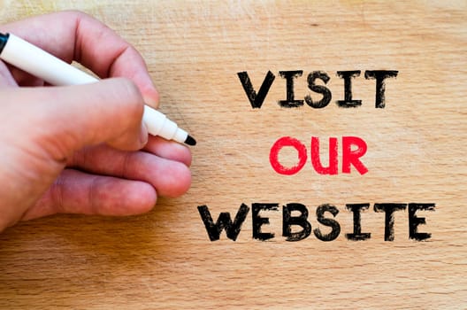 Human hand over wooden background and visit our website text concept