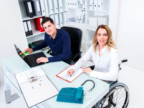 disabled businesswoman in wheelchair and her colleague in the office