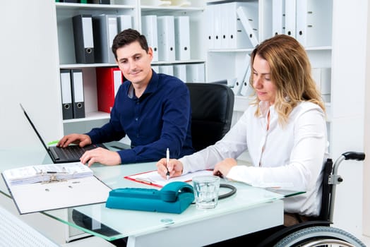 disabled businesswoman in wheelchair and her colleague in the office