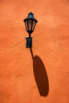 Street light casting a shadow of a red colonial wall in Cartagena, Colombia