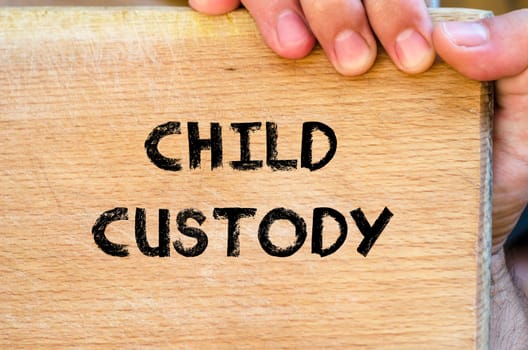 Human hand over wooden background and child custody text concept