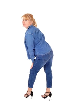 A pretty woman in jeans pants and jacket standing in profile, looking.over her shoulder, isolated for white background..